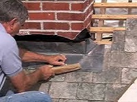 Roof repairer fixing back the leadwork on a slate roof in Carlton FY6